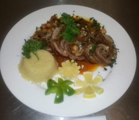 Lamb Shank Tagine & Couscous Garnished with Lemon, Sweet pepper & Basil Image